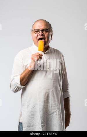 Indischer alter Mann Essen Schokolade Eis in Kegel oder Mango Candy Bar Stockfoto