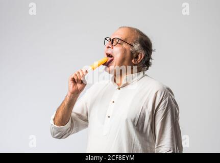 Indischer alter Mann Essen Schokolade Eis in Kegel oder Mango Candy Bar Stockfoto