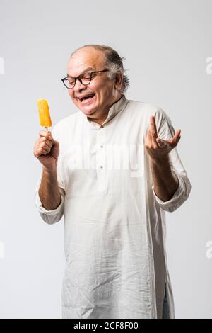 Indischer alter Mann Essen Schokolade Eis in Kegel oder Mango Candy Bar Stockfoto