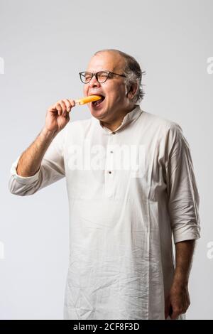 Indischer alter Mann Essen Schokolade Eis in Kegel oder Mango Candy Bar Stockfoto