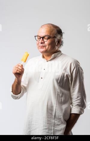 Indischer alter Mann Essen Schokolade Eis in Kegel oder Mango Candy Bar Stockfoto