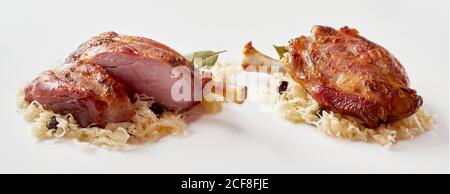 Zwei Portionen Eisbein oder Schweineknöchel auf einem Bett von Sauerkraut in einem Panorama-Banner über weiß für Werbung Stockfoto