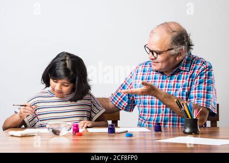 Happy Indian Großvater und kleine Enkelin Malerei mit Pinsel und Wasser Farben. Kinder Kunst. Freizeit mit Enkel Stockfoto