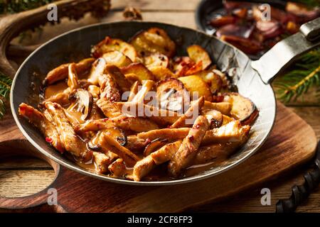 Sautierte würzige Wildwildstreifen mit gebratenen Kartoffelkeilen Gewürzt mit Gewürzen und Chili und serviert in einem rustikalen Skillet oder Pan in Nahaufnahme für Menü Stockfoto