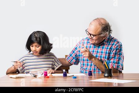 Happy Indian Großvater und kleine Enkelin Malerei mit Pinsel und Wasser Farben. Kinder Kunst. Freizeit mit Enkel Stockfoto