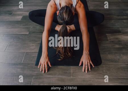 Von oben unkenntlich Frauen in Sportbekleidung konzentriert und liegend Balasana Position auf Sportmatten auf Holzboden in geräumig Fitnessraum Stockfoto