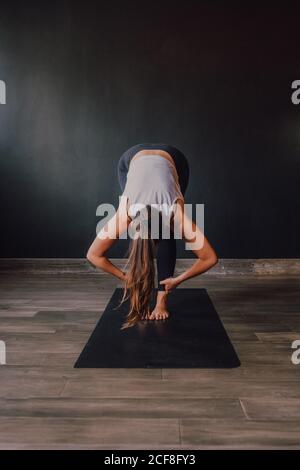 Anonyme, selbstbewusste Frau mit Barfußball in Sportswear, die den Körper auf der Matte streckt und wegschaut, während sie in einem geräumigen, modernen Fitnessraum trainiert Stockfoto
