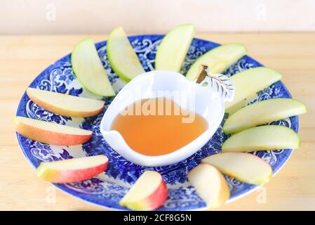 Jüdische Feiertag Rosh Hashana Hintergrund mit Honig und Scheiben von Apple auf hölzernen Tisch. Während das Jüdische Neue Jahr Rosch Haschanah üblich Essen in Scheiben geschnittenen Äpfel in Honig Symbol süßes neues Jahr getaucht. Stockfoto