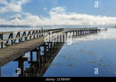 Die historische alte Tokaanu Wharf am Lake Taupo, Neuseeland, erstreckt sich weit hinaus in den ruhigen Gewässern des Sees Stockfoto