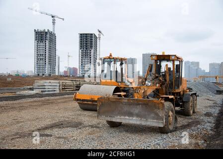 Motor Grader und Bodenverdichter auf einer Baustelle Ebene der Boden und Kiesel für den Bau einer neuen Asphaltstraße. Vibration einfach Stockfoto