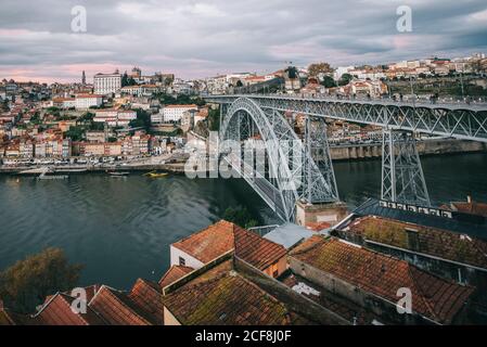 Drone Blick auf erstaunliche Stadtlandschaft mit Brücke über ruhigen Fluss Und Wohnhäuser gegen bewölkten Himmel Stockfoto