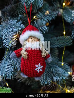 Nettes Baby Mädchen Schneemann handgefertigt. Rot gestrickter Pelzmantel und Mütze, Baumwollzöpfe und Pelzbesatz. Schnee Mädchen Puppe hängen auf einem Zweig eines weihnachtsbaums, f Stockfoto