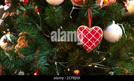 Weihnachtsbaum mit silbernen Kugeln und herzförmigen Lebkuchen verziert. Traditioneller Winterurlaub. Festliche Weihnachten Hintergrund für Stockfoto