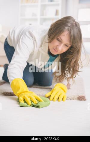 Lächelnde Frau in gelben Gummihandschuhen wischen Staub auf dem Boden Zu Hause Stockfoto