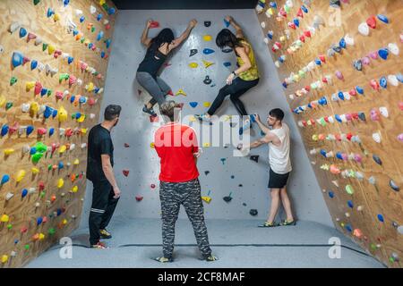 Rückansicht der jungen Gruppe von starken männlichen und weiblichen Kletterer trainieren an der Wand in einem modernen Fitnessstudio Stockfoto