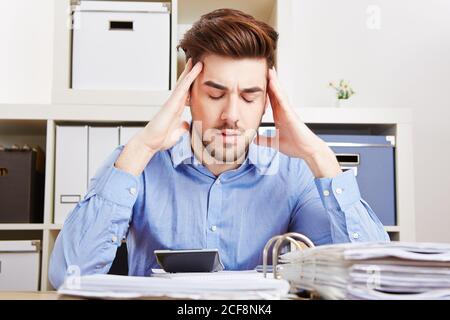 Geschäftsmann mit Burnout im Büro massiert seine schmerzenden Tempel Stockfoto