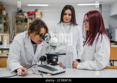 Frau mit Mikroskop in der Nähe von Kollegen im Labor Stockfoto
