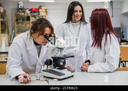 Frau mit Mikroskop in der Nähe von Kollegen im Labor Stockfoto