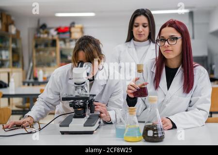 Frau mit Mikroskop in der Nähe von Kollegen im Labor Stockfoto
