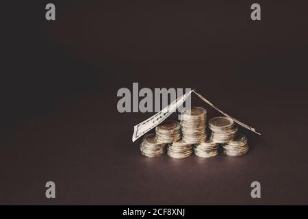 Münzen Stapel von der Rechnung in Form eines Hauses abgedeckt. Konzept von Geldsparen und Einkommen Anlageideen und Finanzmanagement für die Zukunft. Stockfoto