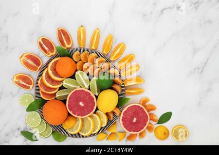 Zitrusfrüchte reich an Antioxidantien & Vitamin C, mit Orangen, Zitronen, Limetten, Mandarinen & Grapefruit auf Tellern. Auch hoch in Anthocyanen, Lycopin & d Stockfoto