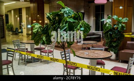 Bloomington, Indiana, USA. August 2020. Tische und Stühle, die durch ein Fenster abgebildet sind, sind in der Spruce Hall auf dem Campus der Indiana University abgesperrt, wo einige Studenten nach der ersten Herbstwoche während der Coronavirus-Pandemie in Quarantäne gestellt werden.über 30 griechische Häuser an der Indiana University befinden sich derzeit in Quarantäne. Quelle: Jeremy Hogan/SOPA Images/ZUMA Wire/Alamy Live News Stockfoto