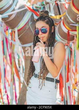 Stilvolle junge Frau trägt Sonnenbrille fürchten trinken Cocktail während draußen festival und Blick auf die Kamera Stockfoto