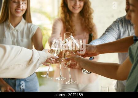 Team. Die Leute klirren Gläser mit Wein oder Champagner. Fröhliche fröhliche Freunde feiern Feiertage, Treffen. Nahaufnahme von lächelnden Freunden, Lebensstil. Party zu Hause oder im Restaurant, Café. Stockfoto