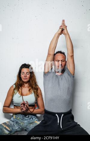 Mann und Frau im Gebet Asana stehen und Baum Pose auf weißem Hintergrund mit geschlossenen Augen Stockfoto