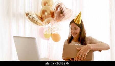 Frau öffnet Geschenk vor dem Geburtstagslaptop Stockfoto