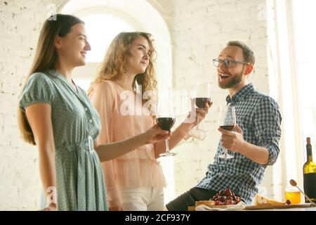 Vibes. Die Leute klirren Gläser mit Wein oder Champagner. Fröhliche fröhliche Freunde feiern Feiertage, Treffen. Nahaufnahme von lächelnden Freunden, Lebensstil. Party zu Hause oder im Restaurant, Café. Stockfoto
