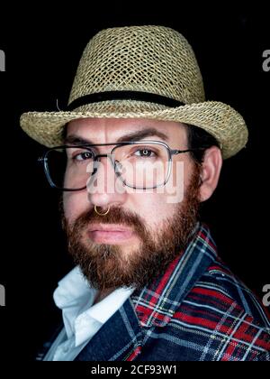 Schöner bärtiger Mann in Brille und Blick auf die Kamera auf Schwarzer Hintergrund Stockfoto