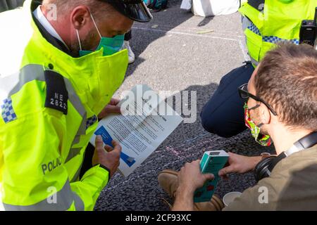 Ein Polizeibeamter liest einem Protestierenden während der Extinction Rebellion Demonstration, London, 1. September 2020, einen Befehl der Sektion 14 vor Stockfoto