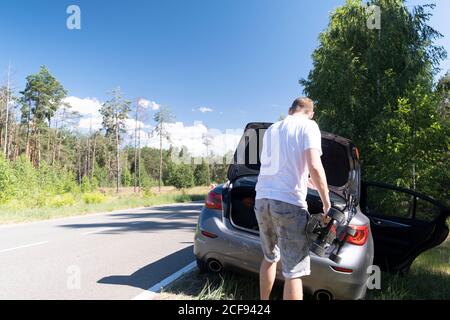 Man nahm ein Skateboard aus dem Kofferraum eines Auto an einem sonnigen Sommertag entlang der Straße geparkt Stockfoto