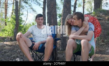Gruppe von Freunden sitzen auf Campingstühlen in einer Kiefer Wald und Kommunikation Stockfoto