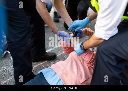 Polizeibeamte legen Handschellen auf einer Protestblockstraße während der Extinction Rebellion Demonstration, London, 1. September 2020 Stockfoto