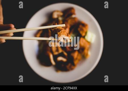 Von oben Hand essen serviert appetitlich heißen Schweinebauch mit Gemüse wie Gurke und Paprika mit Essstäbchen Stockfoto