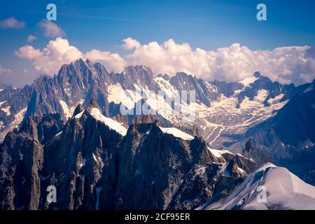 Weiße, scharfe Berggipfel im Schnee, die bis zu Wolken aufsteigen Himmel Stockfoto