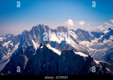 Weiße, scharfe Berggipfel im Schnee, die bis zu Wolken aufsteigen Himmel Stockfoto