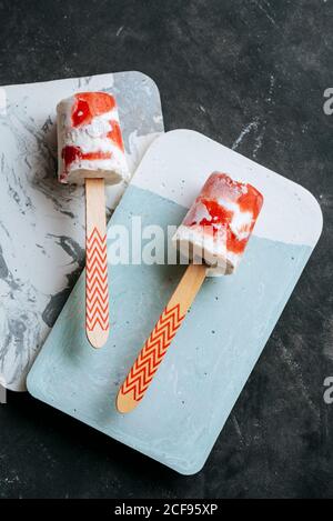Draufsicht auf zwei Wassermelonen und cremige Eiszapfen Schicke Gerichte auf dunklem Hintergrund Stockfoto