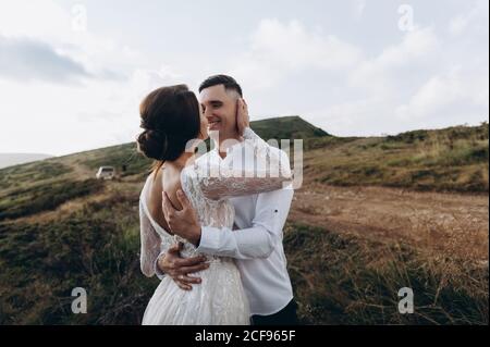 Ein paar Brautpaare, die im Hintergrund der Berge stehen. Stockfoto