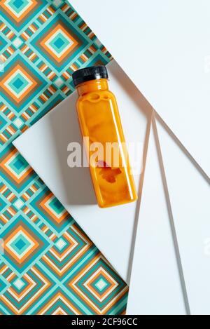 Mango- und Kürbis-Smoothie-Flasche über geometrischen Strukturen im Retro-Stil. Von oben Stockfoto