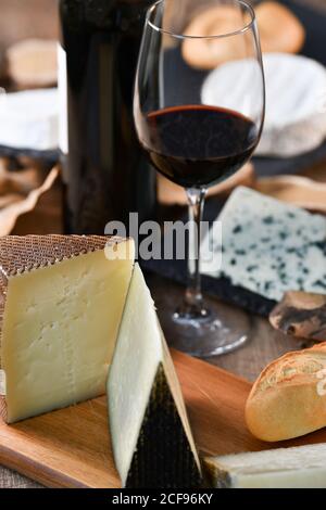 Leckere hausgemachte Scheiben Weißkäse und frisches knuspriges Brot Mit Flasche und Glas Rotwein auf rustikalem Holz Tabelle Stockfoto