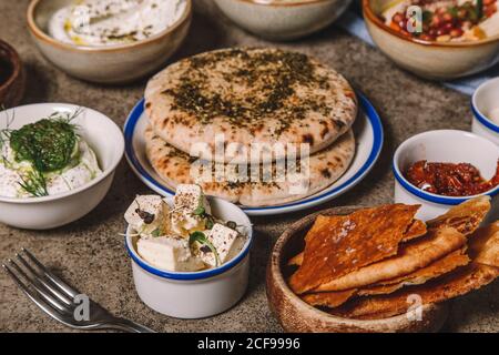 Serviert Gerichte mit Käse, Hummus und geriebenem Fleisch mit Fladenbrot auf grauem Tisch Stockfoto