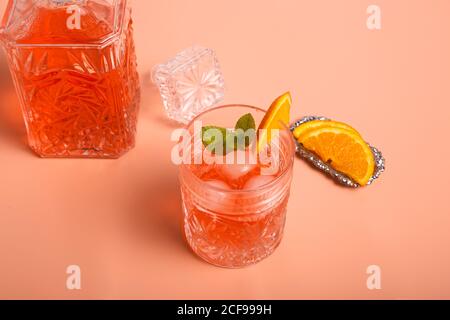 Von oben ein Glas frischer kalter Cocktail mit Eis Würfel und Minze auf bunten Hintergrund mit Scheiben von platziert Reife Orange Stockfoto