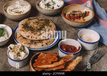 Serviert Gerichte mit Käse, Hummus und geriebenem Fleisch mit Fladenbrot auf grauem Tisch Stockfoto