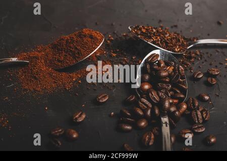Arten von Kaffeesatz Instant und Pulver und Kaffeebohnen In Löffeln auf schwarzem Tisch Stockfoto