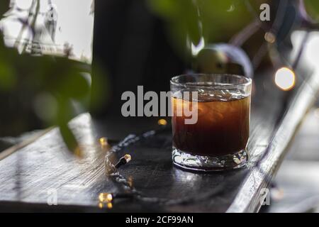 Selektive Fokusaufnahme eines Glases schwarzen Eiskaffees Auf einem Kaffeetisch mit Lichtern Stockfoto