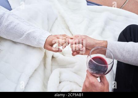 Von oben Seitenansicht des fröhlichen jungen Paares in Casual Tragen Sie Toasting mit Gläsern Rotwein, während Sie glücklich genießen Momente zusammen Stockfoto