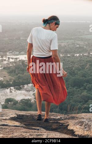 Rückansicht einer unkenntlich Reisenden Frau in legerer Kleidung und Bandana, die während des Urlaubs in Sigiriya die malerische Landschaft bewundert Stockfoto